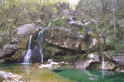 a waterfall on the side of a mountain with a pool of water at Apartma Bubi in Bovec