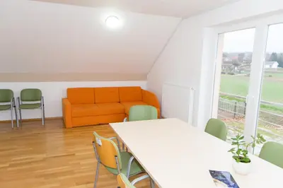 an office with an orange couch and a table and chairs at Apartma Murania in Lendava