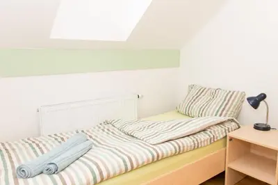 a bed with striped sheets and a lamp on a table at Apartma Murania in Lendava