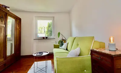 a living room with a green couch and a table at Bergmannhaus in Zagorje ob Savi