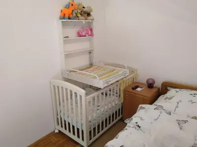 a crib in a bedroom next to a bed at Apartment Trobentica 40 Moravske Toplice - SPA in Moravske Toplice