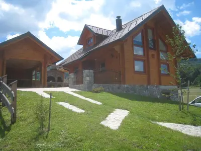 a large wooden house with a grass yard in front of it at House of Nature Tajhte in Planina pri Sevnici