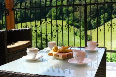 a table with a bowl of fruit and cups on a balcony at House of Nature Tajhte in Planina pri Sevnici