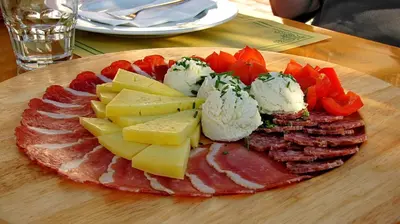 a plate of food with meats and cheese on a table at Tourist Farm Kranjc in Kobarid