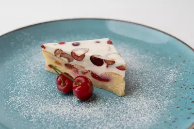 a piece of cake on a blue plate with cherries at Tourist Farm Kranjc in Kobarid