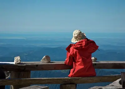 a person in a red jacket sitting on a wooden railing at Tourist Farm Kranjc in Kobarid