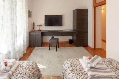 a bedroom with two beds and a desk with a television at Villa Magnolia in Ljubljana