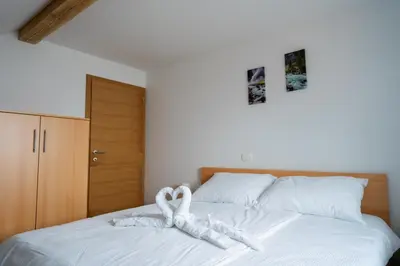 a bed with a white towel in the shape of a heart at PJagodic Apartments & Wellness in Cerklje na Gorenjskem