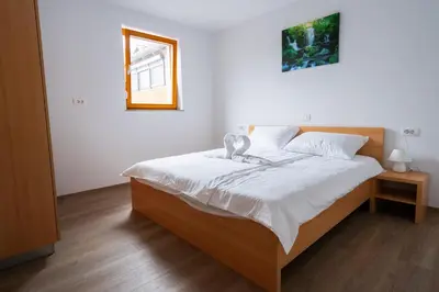 a bedroom with a bed with white sheets and a window at PJagodic Apartments & Wellness in Cerklje na Gorenjskem