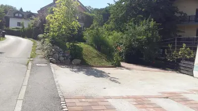 an empty street next to a house with bushes at ANERI in Ljubljana