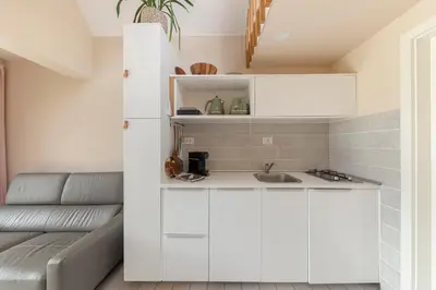 a kitchen with white cabinets and a couch at Garden living in Bled