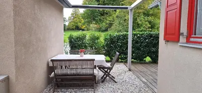 a table and chairs on a patio with a red door at Garden living in Bled
