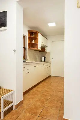 a kitchen with white cabinets and a tile floor at Wineyard getaway house in Sevnica