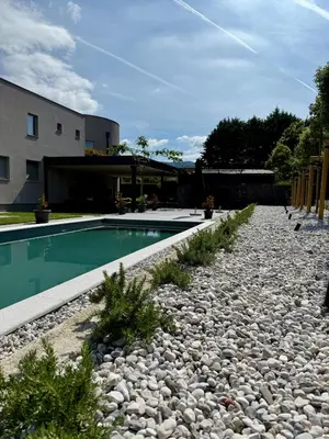 a backyard with a swimming pool and rocks and a building at DAM boutique hotel & restaurant in Nova Gorica