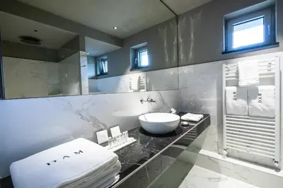 a white bathroom with a sink and a mirror at DAM boutique hotel & restaurant in Nova Gorica