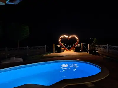 a heart shaped sign is lit up at night at SECRET WELLNESS in Bodonci