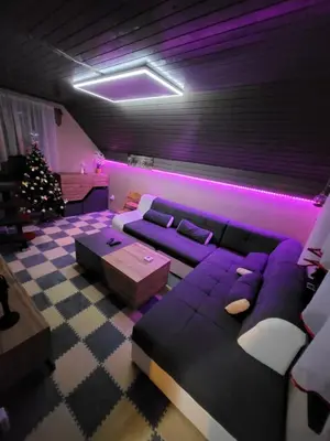a living room with a purple couch and a christmas tree at Alpinejka House in Tržič