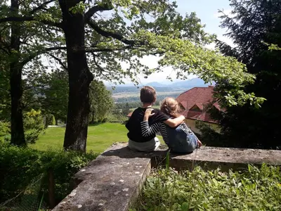 a man and a woman sitting on a stone wall at Alpinejka House in Tržič