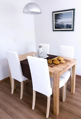 a dining room table with white chairs and a wooden table with food on it at Apartmaji Baron in Bled