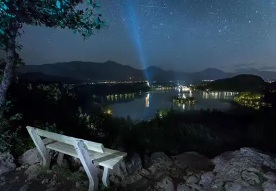 a bench sitting on top of a hill at night at Apartmaji Baron in Bled