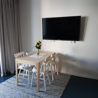 a table with chairs and a vase of flowers on it at Genius Guest Unique Banovci Apartment in Banovci