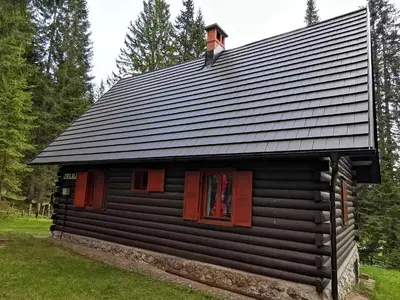 a log cabin with red windows and a roof at Chalet Stara Jelka Pokljuka in Zgornje Gorje