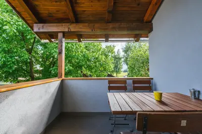 a wooden table and chairs on a porch with a window at Blue Door in Lesce
