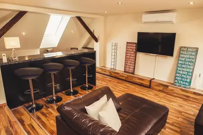 a living room with a leather couch and a bar at SKOL apartments in Celje