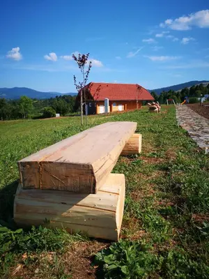 a wooden platform in a field with a house in the background at Camp The sunrise hill in Pivka
