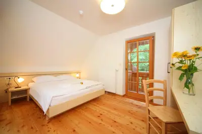 a bedroom with a bed and a table and a window at Planinski dom Savica in Bohinj