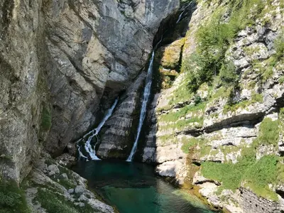 a waterfall flows into a river in a canyon at Planinski dom Savica in Bohinj