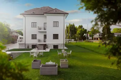 a white building with tables and chairs in the yard at Vila Ula La Luxury Apartments in Bled