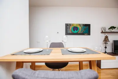 a wooden table with two plates and two wine glasses at Bright 2-Bed Apartment Free Parking & WiFi - Walk to Old Town in Ljubljana