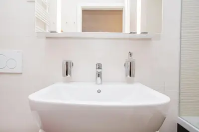 a white bathroom with a sink and a mirror at Bright 2-Bed Apartment Free Parking & WiFi - Walk to Old Town in Ljubljana