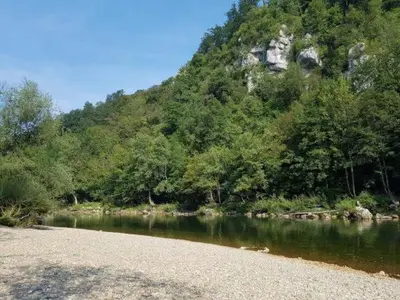 a river with a rocky shore and a mountain at Apartma Lahinja in Gradac
