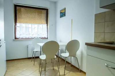 a kitchen with white chairs and a table and a window at Apartmaji Anja in Bled
