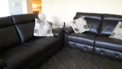 a black leather couch with two pillows on it at Kramer Hiša in Kobarid