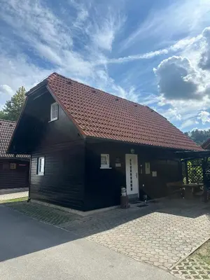 a black building with a red roof at Bella Mura Nature House I26 in Podčetrtek