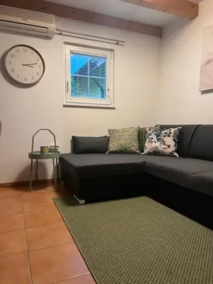 a living room with a couch and a clock on the wall at Bella Mura Nature House I26 in Podčetrtek