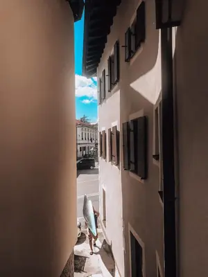 a man walking down a alley with a surfboard at Pr' Kramarju - House in the heart of Kobarid in Kobarid