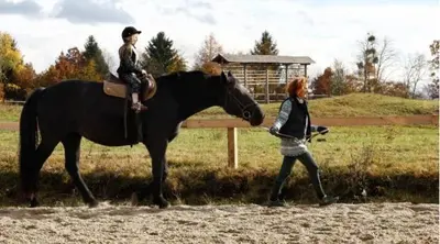 a woman walking next to a child on a horse at CARNIOLAN HOUSE - GORENSKA HIŠKA in Radovljica