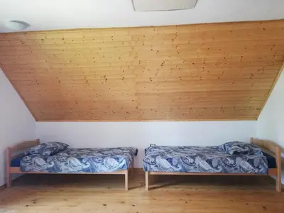 two beds in a room with wooden ceilings at Guest House Nanos in Vipava