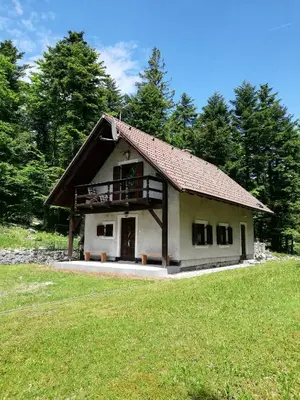 a small white house with a porch on a field at Guest House Nanos in Vipava