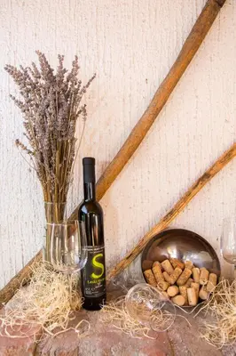 a bottle of wine next to a vase and a bowl of peanuts at Vinska klet Smej in Lendava