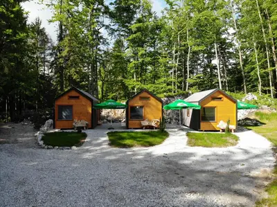 two cottages with green umbrellas in the woods at Estate Marjetin dom in Idrija