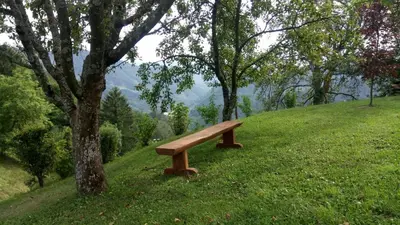 a wooden bench sitting on top of a hill at Apartma na Ravnicah in Cerkno