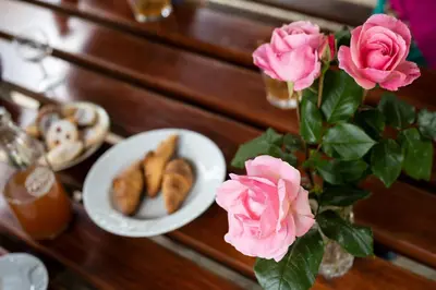 a table with a plate of pastries and pink roses at Domačija Vesel in Trebnje