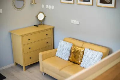 a yellow couch with two pillows on it next to a dresser at Apartments Stankovo in Krška Vas