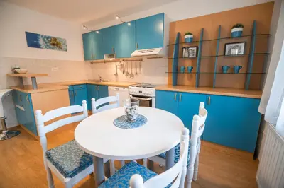 a kitchen with blue cabinets and a white table and chairs at Apartments Stankovo in Krška Vas