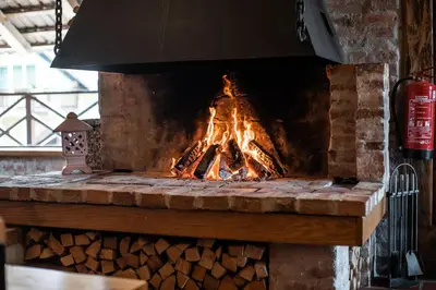 a fire in a stone fireplace with a pile of wood at Apartment with Sauna pr' Geči in Dobova